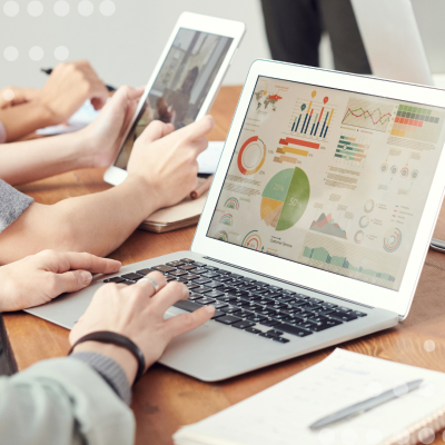 Image of workers at a desk on their laptops showing data